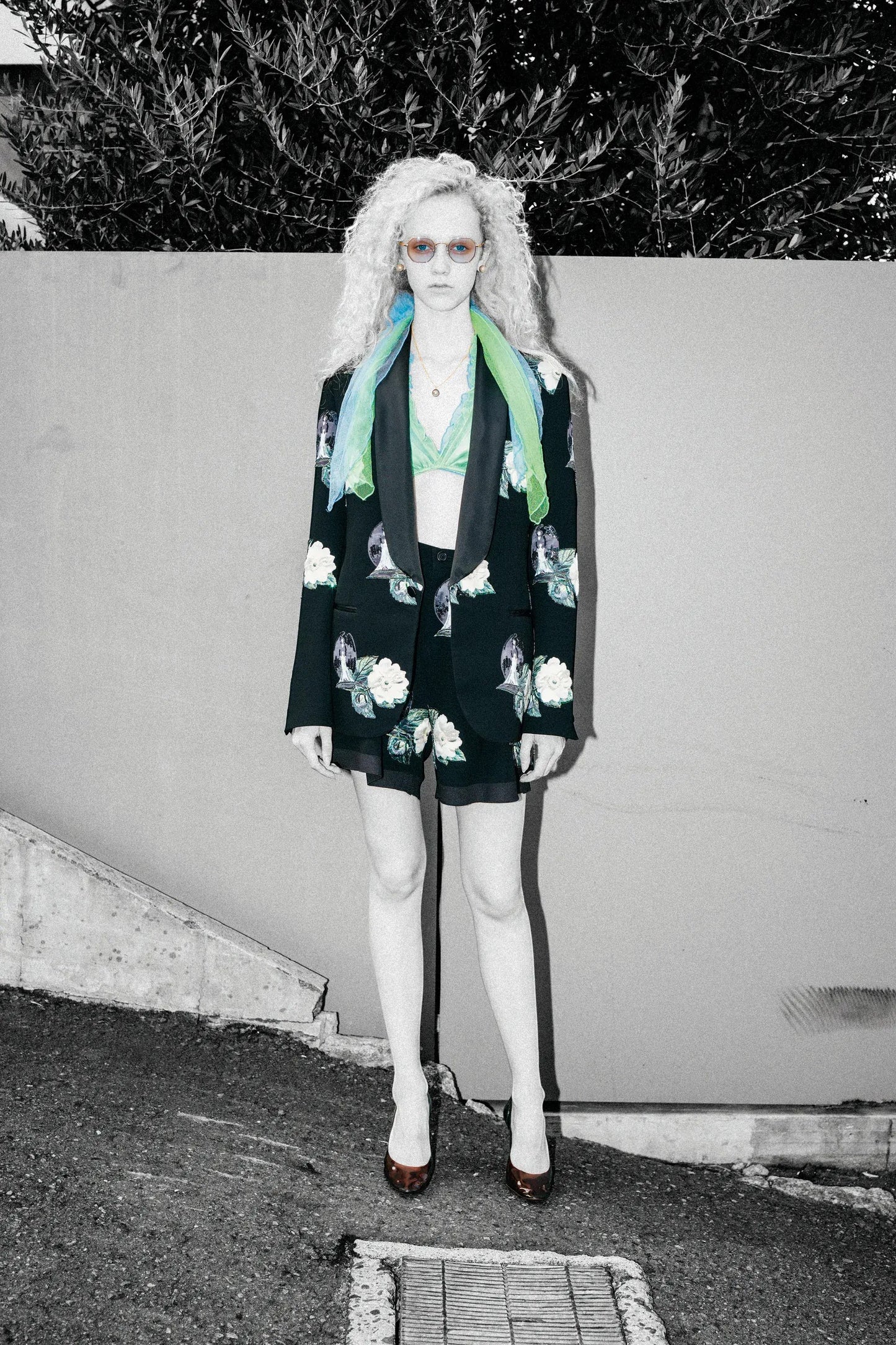 Tasoni black single-breasted blazer with embroidered white roses and floral patches, lapel collar, paired with matching shorts and a green bralette.