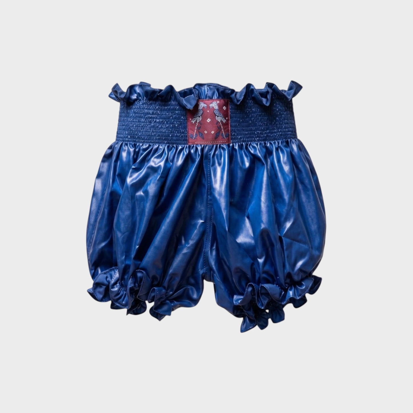 Tasoni Conner Ives blue nylon bloomer shorts with a ruffled waistband, smocked detail, and ruffled leg openings.