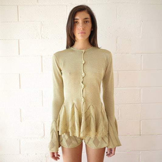 Tasoni Conner Ives gold knitted pointelle godet cardigan with flared sleeves worn by a model against a white wall.