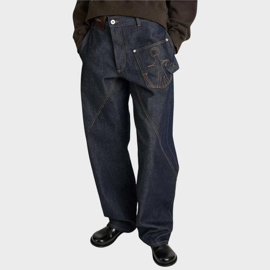 Tasoni JW Anderson dark indigo denim jeans with twisted workwear seams and embroidered pocket detail on model.