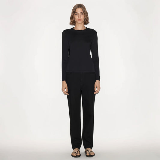 Model wearing a black Partow Marden long sleeve top with a crew neck, paired with black trousers by Tasoni.