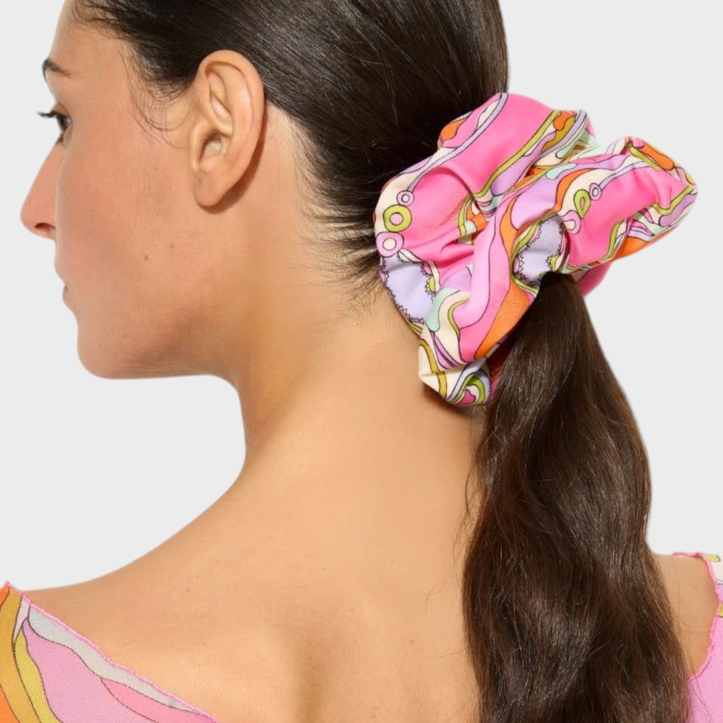 Model wearing a Tasoni Pucci zipped silk scrunchie with a vibrant pink and orange abstract geometric print.