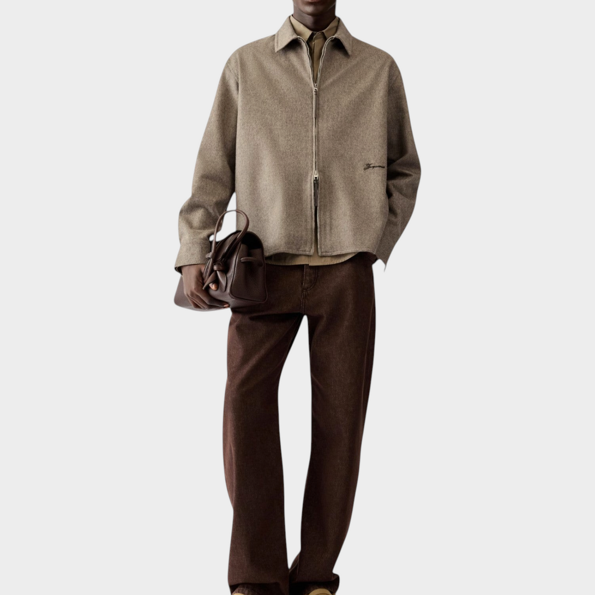 Tasoni Jacquemus La Chemise Flash beige wool zipped shirt worn with brown trousers and a dark leather handbag