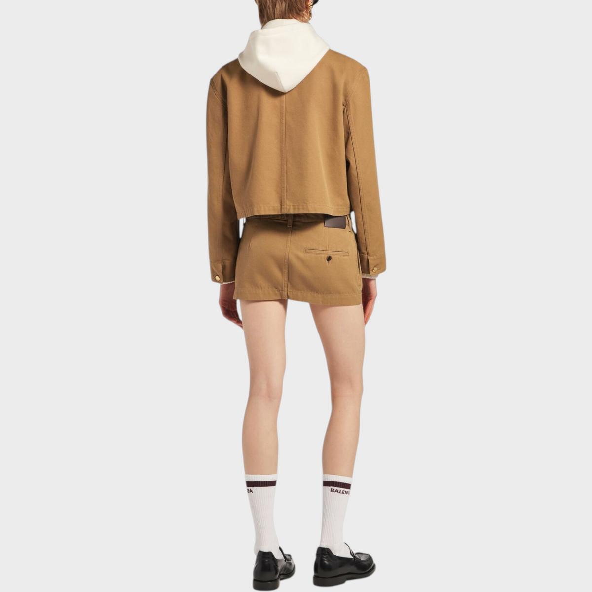 Tasoni Balenciaga cropped tan workwear jacket with a white hood worn over a matching mini skirt from the back