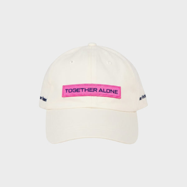 Tasoni x Jan Vorisek white cotton baseball cap with pink "TOGETHER ALONE" embroidered patch and blue text.