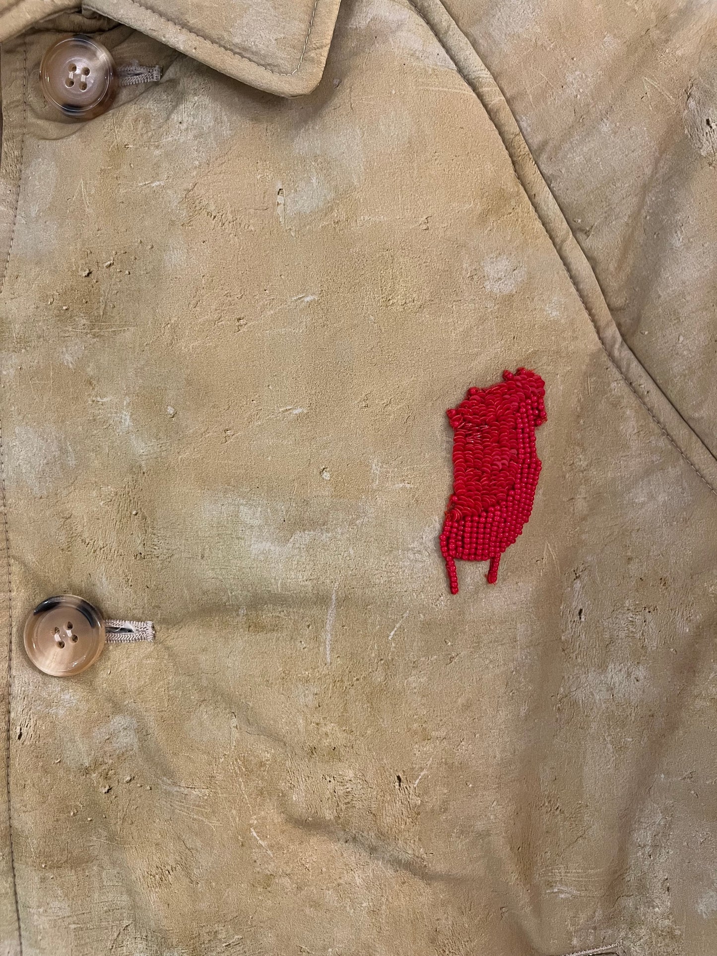 Tasoni beige oversized padded coat with a red beaded embroidered patch and tortoiseshell buttons.