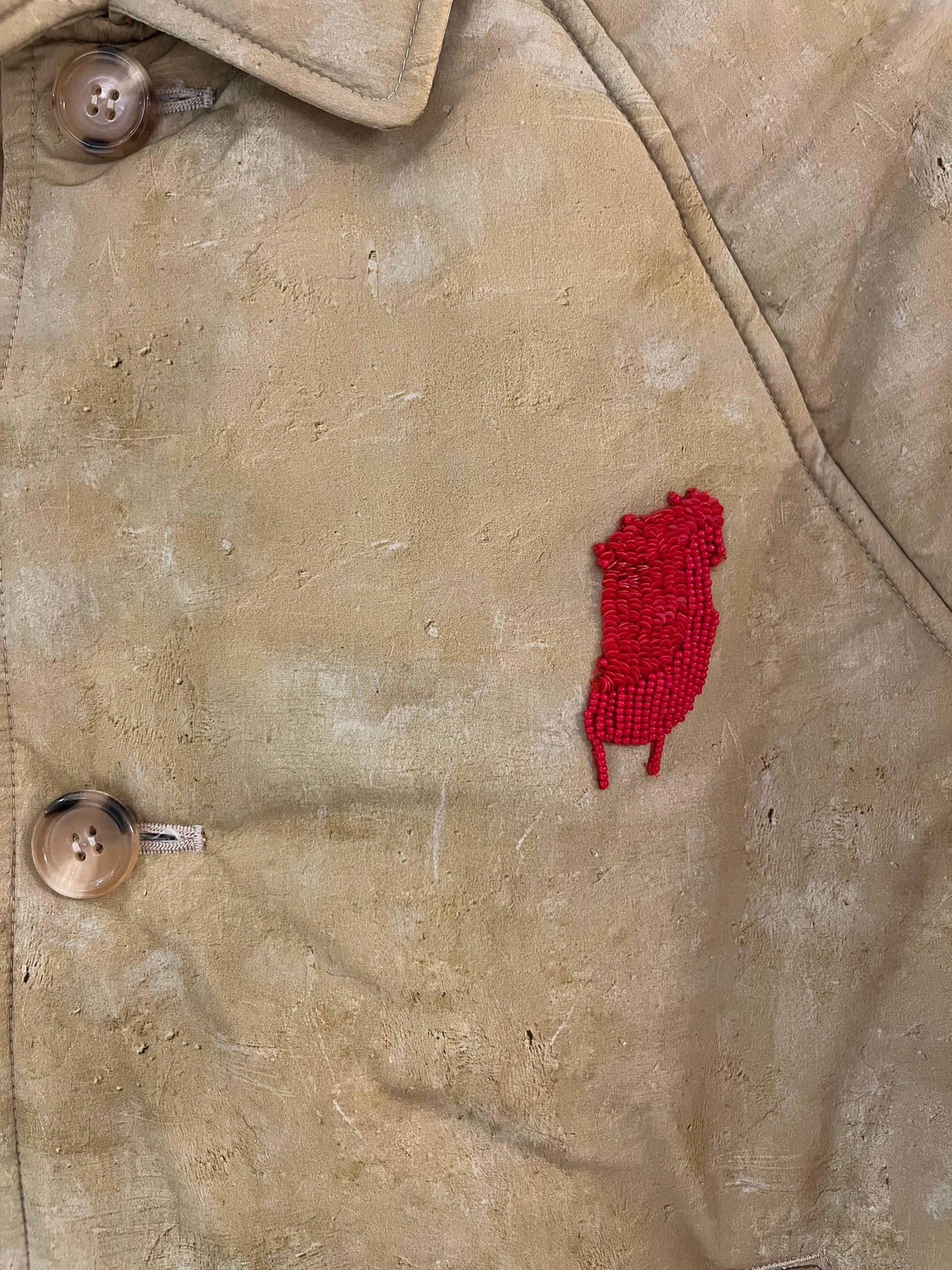 Tasoni beige oversized padded coat with a red beaded embroidered patch and tortoiseshell buttons.
