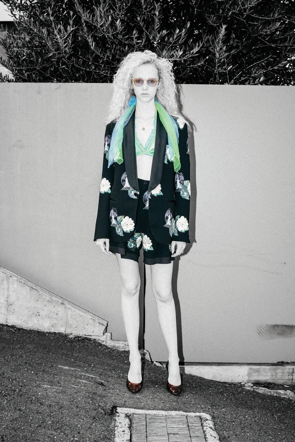 Tasoni black single-breasted blazer with embroidered white roses and floral patches, lapel collar, paired with matching shorts and a green bralette.