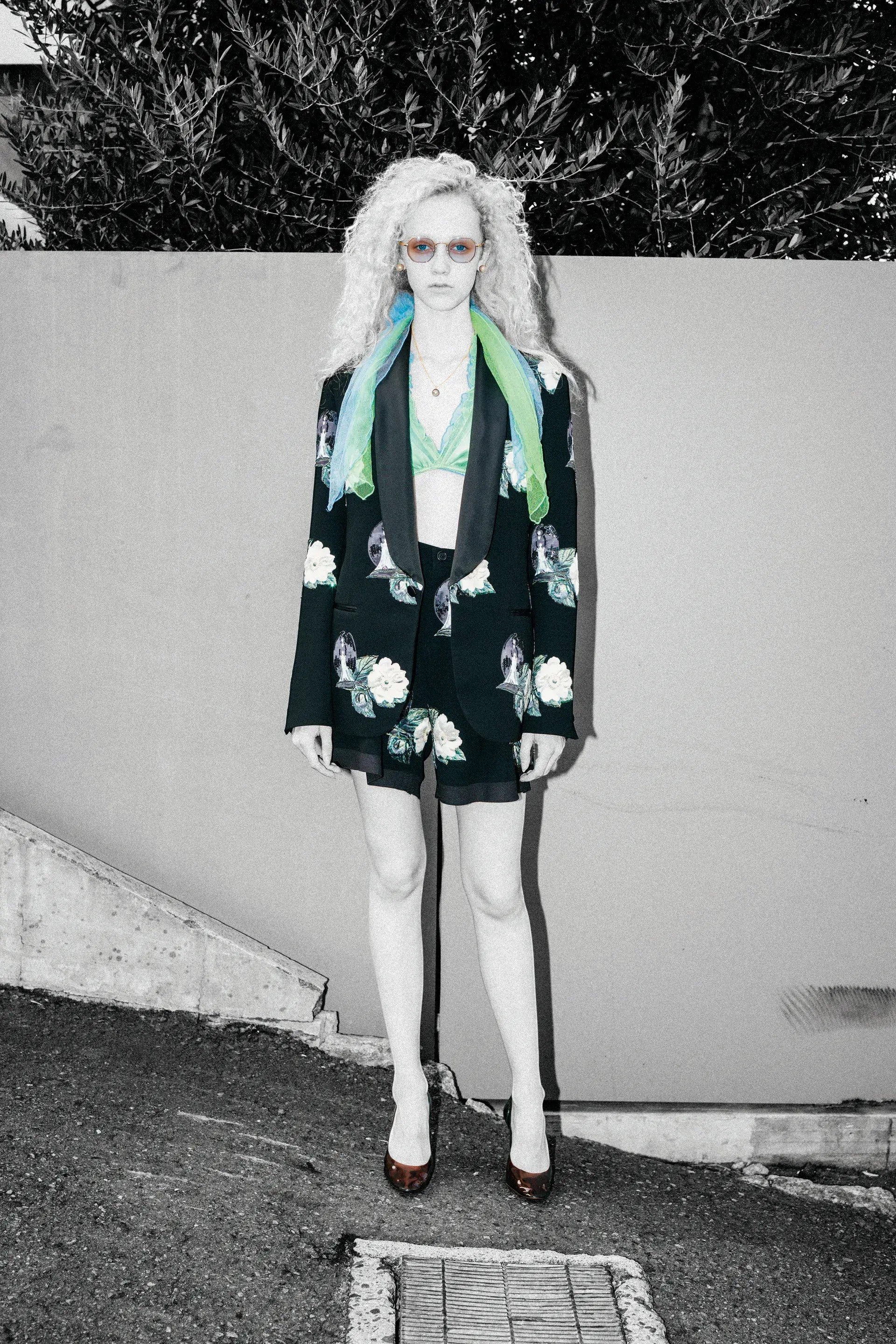 Tasoni black single-breasted blazer with embroidered white roses and floral patches, lapel collar, paired with matching shorts and a green bralette.
