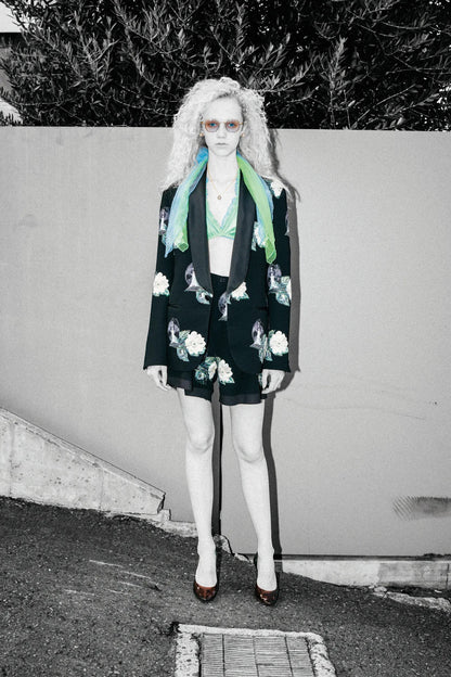 Tasoni black single-breasted blazer with embroidered white roses and floral patches, lapel collar, paired with matching shorts and a green bralette.