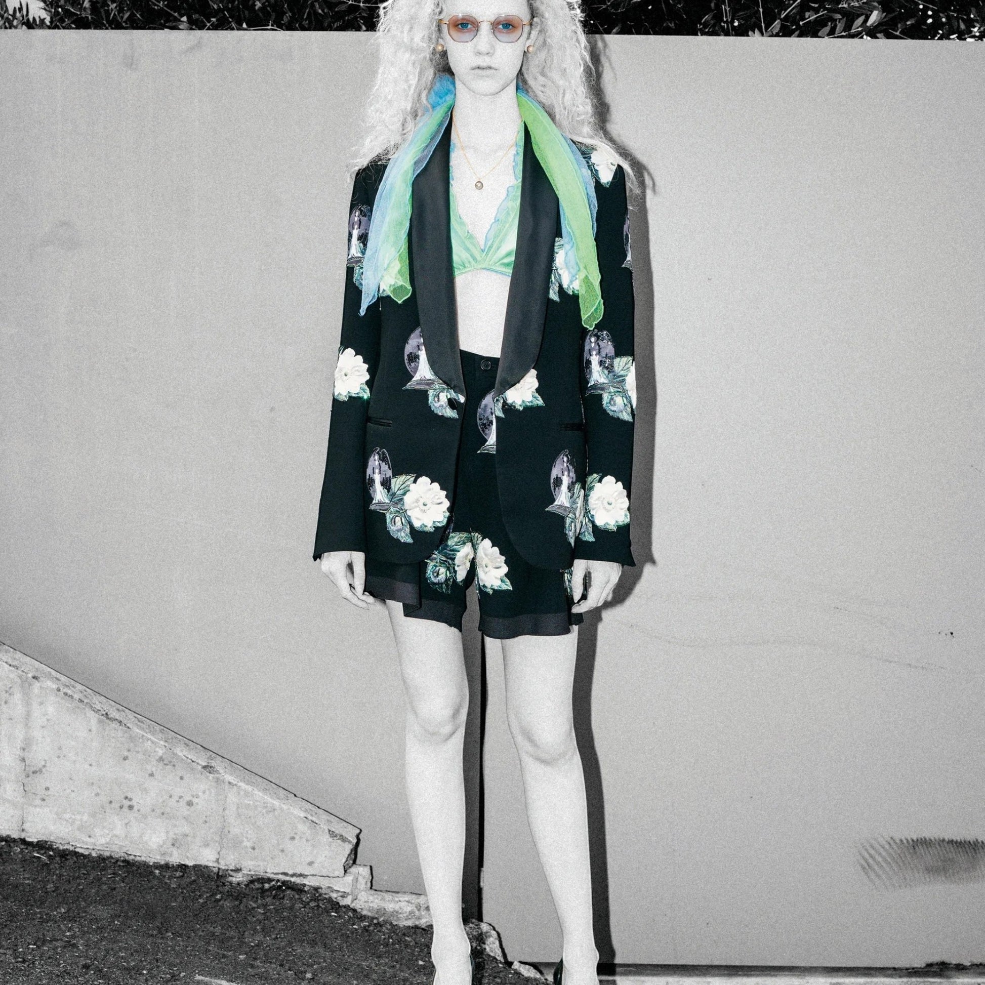 Tasoni black high-waist shorts with embroidered rose patches and front pleats, paired with a matching blazer and green bralette.