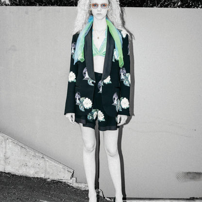 Tasoni black high-waist shorts with embroidered rose patches and front pleats, paired with a matching blazer and green bralette.
