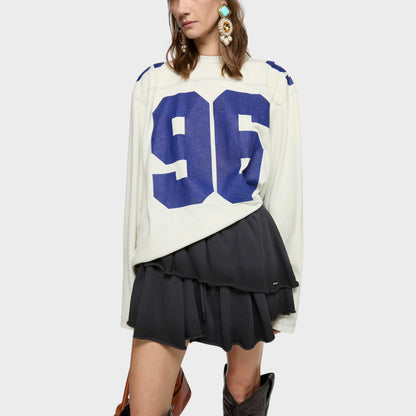 Tasoni black tiered ruffle mini skirt with drawstring waist and raw hem. Model wears with a cream long-sleeve top.