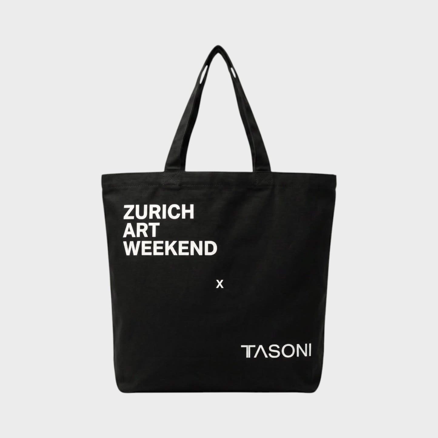 Tasoni black canvas tote bag with white "ZURICH ART WEEKEND x TASONI" print. Simple design with two shoulder straps.