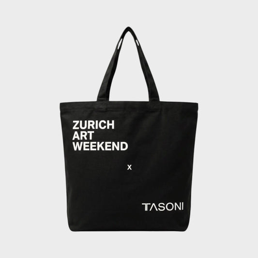 Tasoni black canvas tote bag with white "ZURICH ART WEEKEND x TASONI" print. Simple design with two shoulder straps.