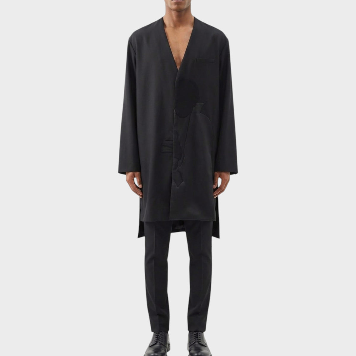 Tasoni black wool asymmetric collarless coat with Dracula motif, worn by a male model with black trousers and shoes.
