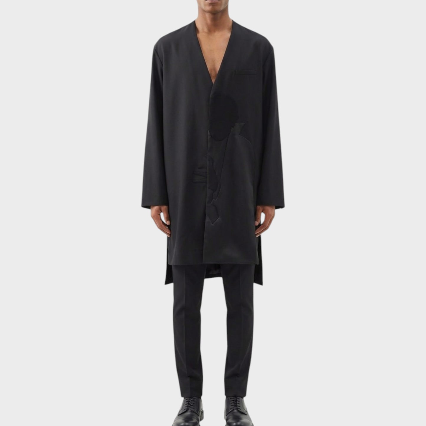 Tasoni black wool asymmetric collarless coat with Dracula motif, worn by a male model with black trousers and shoes.