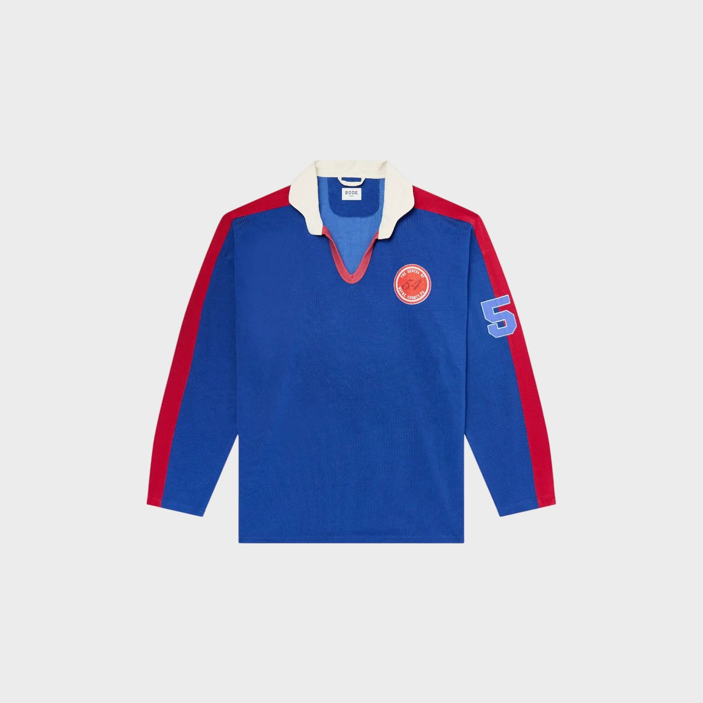 Tasoni blue long sleeve polo shirt with red trim, white collar, and embroidered patches on chest and sleeve.