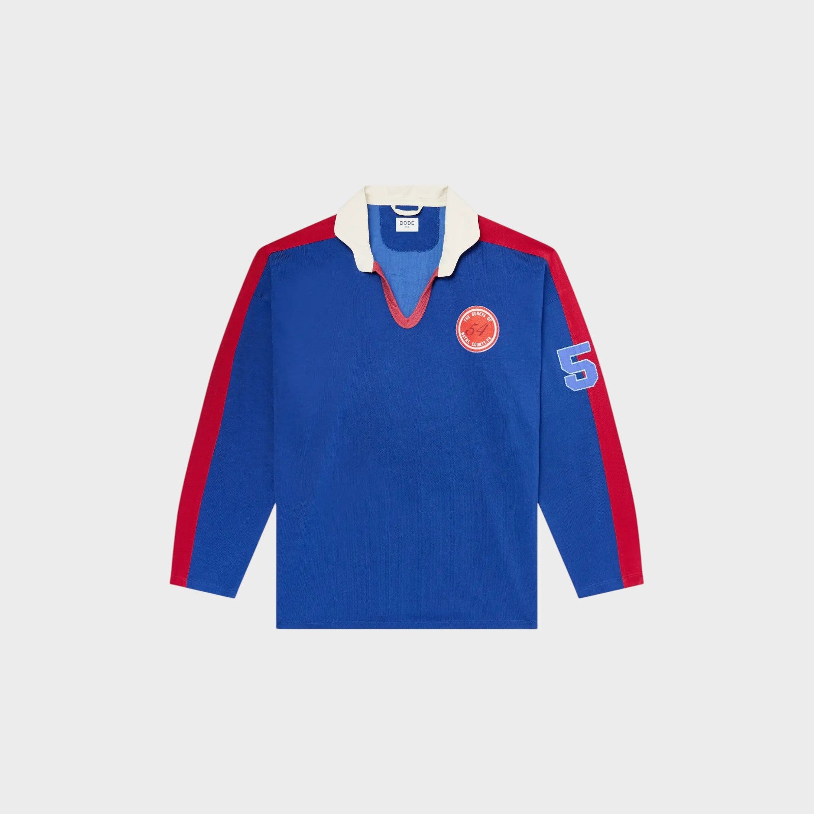Tasoni blue long sleeve polo shirt with red trim, white collar, and embroidered patches on chest and sleeve.