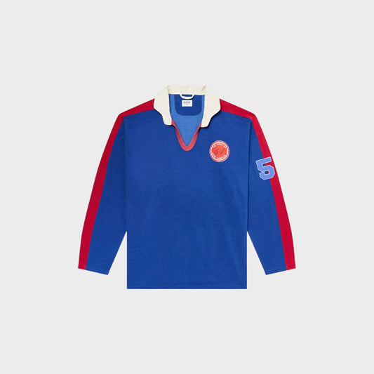 Tasoni blue long sleeve polo shirt with red trim, white collar, and embroidered patches on chest and sleeve.
