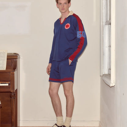Tasoni blue long sleeve v-neck polo with red accents and '50' patch on sleeve, paired with matching shorts.
