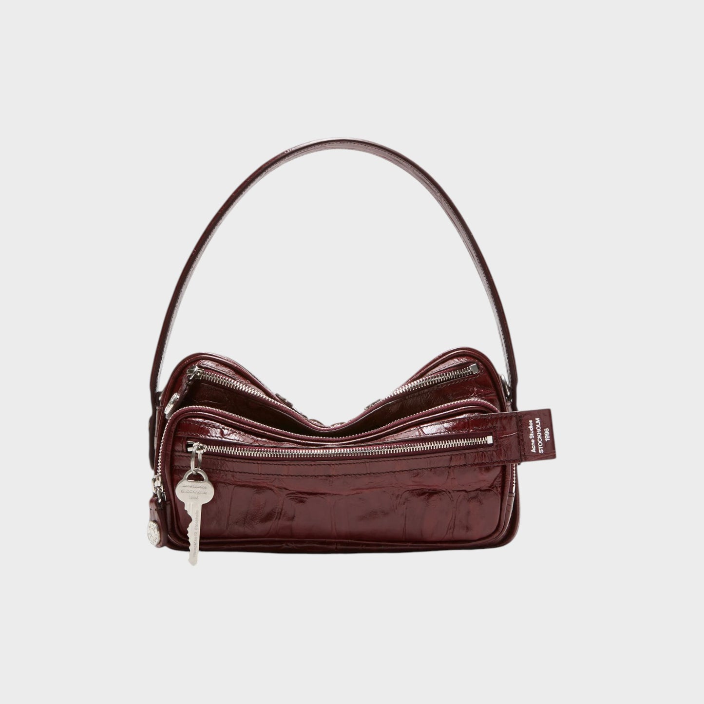 Tasoni burgundy patent leather shoulder bag with croc-effect texture and silver key charm.