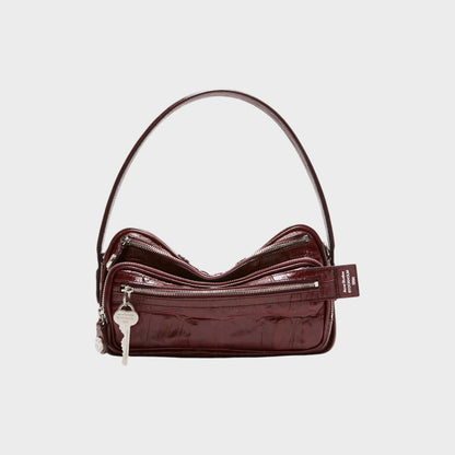 Tasoni burgundy patent leather shoulder bag with croc-effect texture and silver key charm.