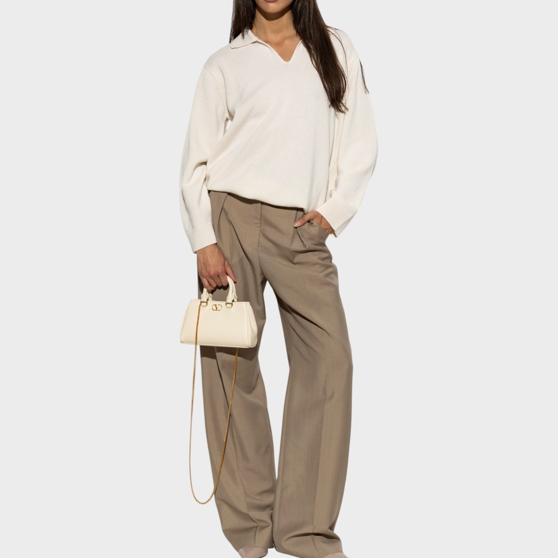Tasoni cream cashmere V-neck polo sweater with wide-leg taupe trousers and a cream handbag.