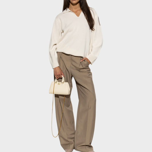 Tasoni cream cashmere V-neck polo sweater with wide-leg taupe trousers and a cream handbag.