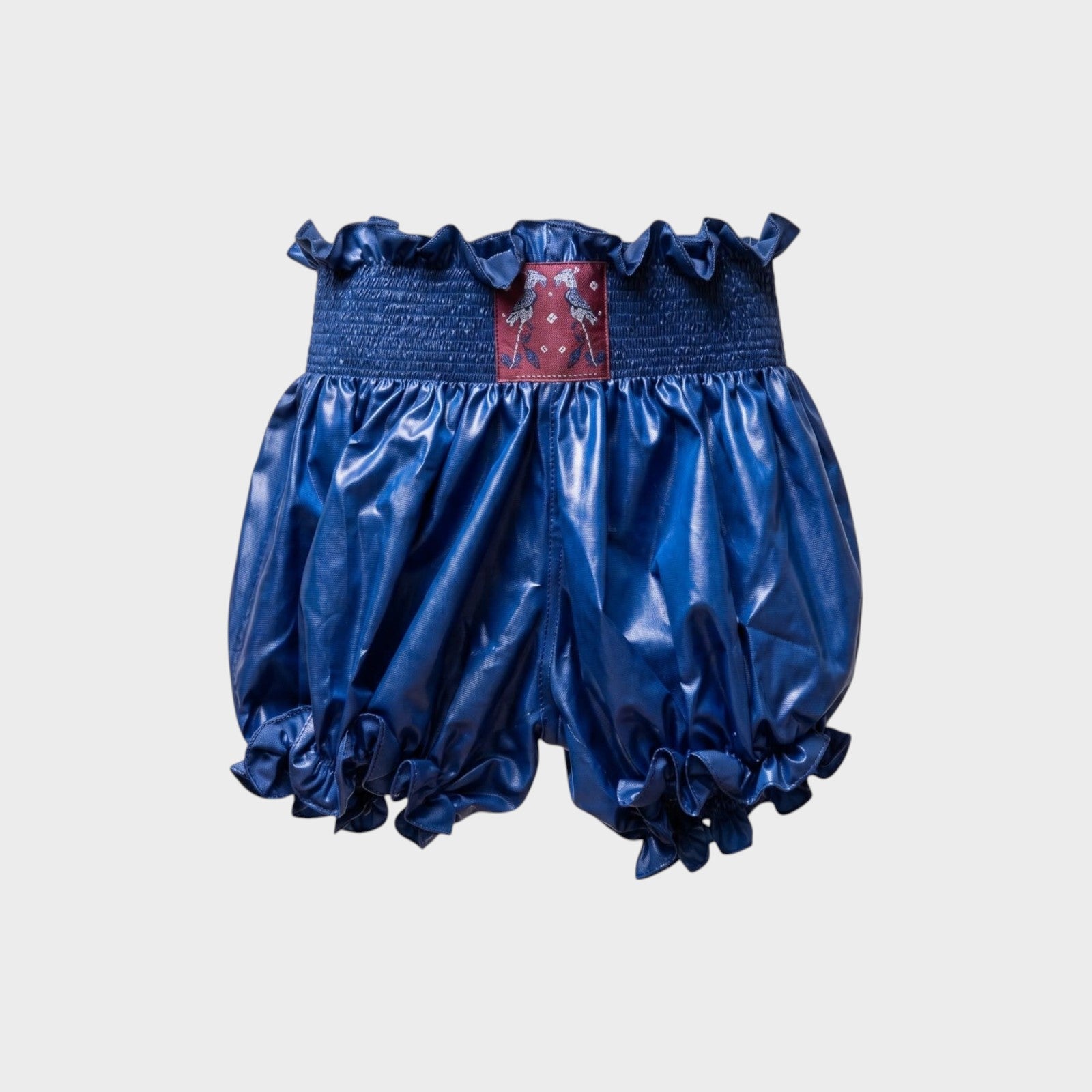 Tasoni Conner Ives blue nylon bloomer shorts with a ruffled waistband, smocked detail, and ruffled leg openings.