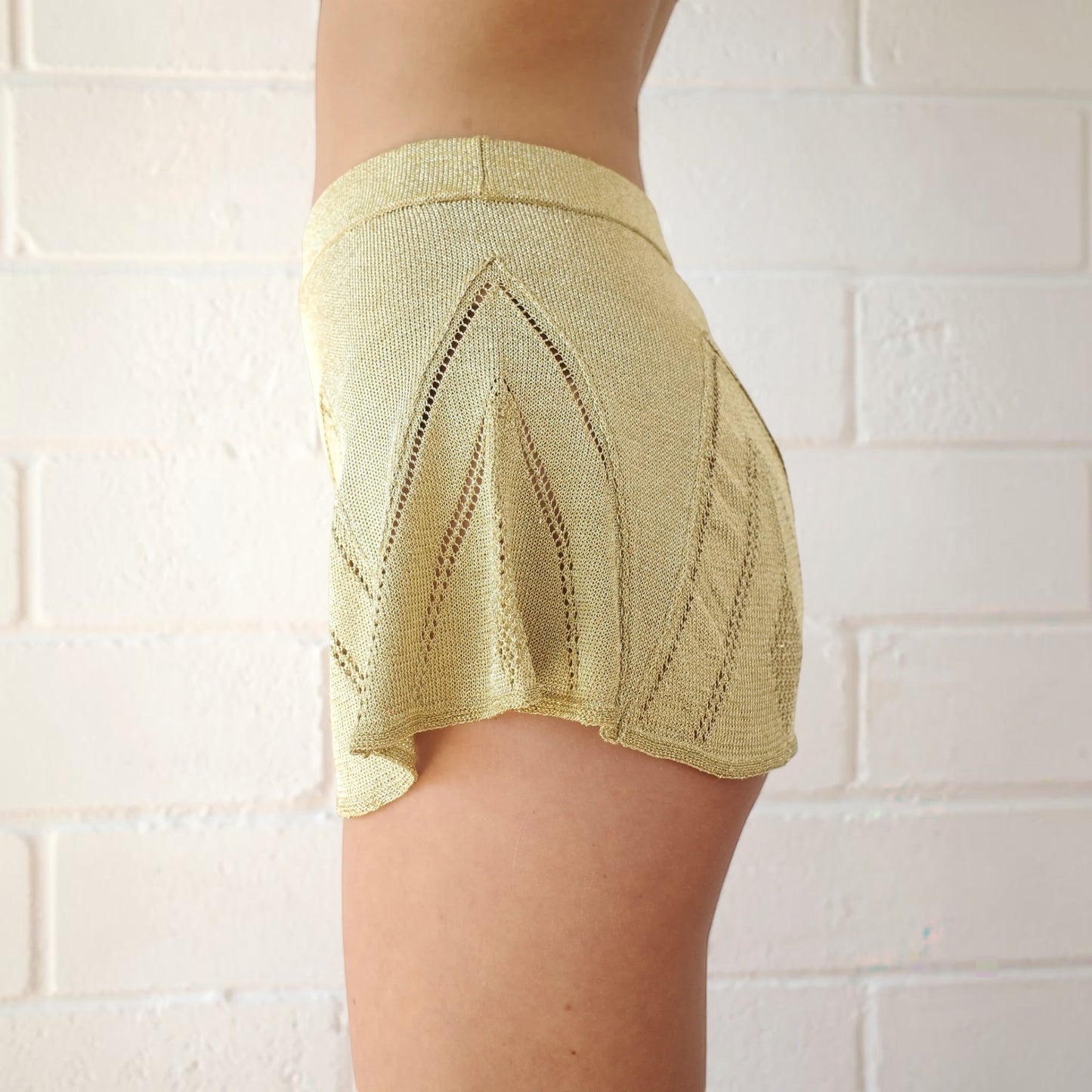 Tasoni Conner Ives gold knitted pointelle godet shorts with a high-waisted fit and delicate openwork detailing.