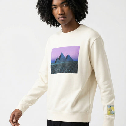 Tasoni cream cotton crew neck sweatshirt with a graphic print of pyramids under a purple sky on the front and a cartoon graphic on the sleeve.