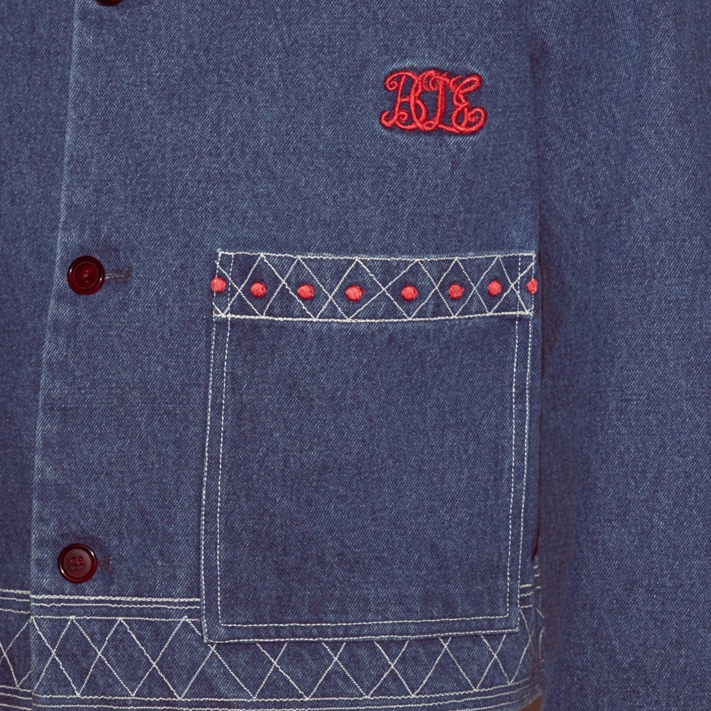 Tasoni blue embroidered denim jacket with red geometric pattern detail on pocket and red buttons.