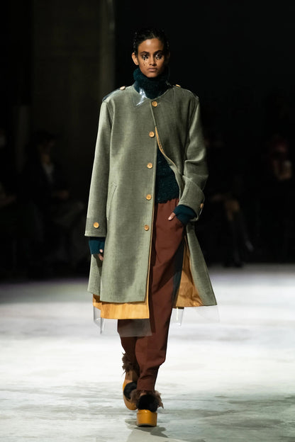 Tasoni moss green button-up coat with transparent collar and hem detail, worn by a model on a runway.