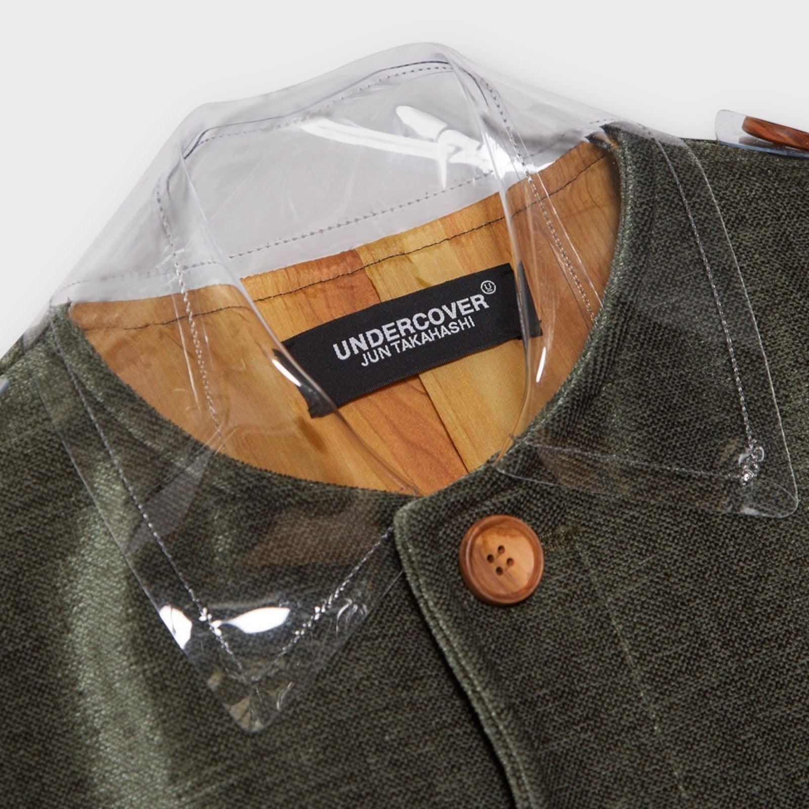 Tasoni Undercover moss green button-up coat with transparent collar and hem detail, featuring a wooden button.