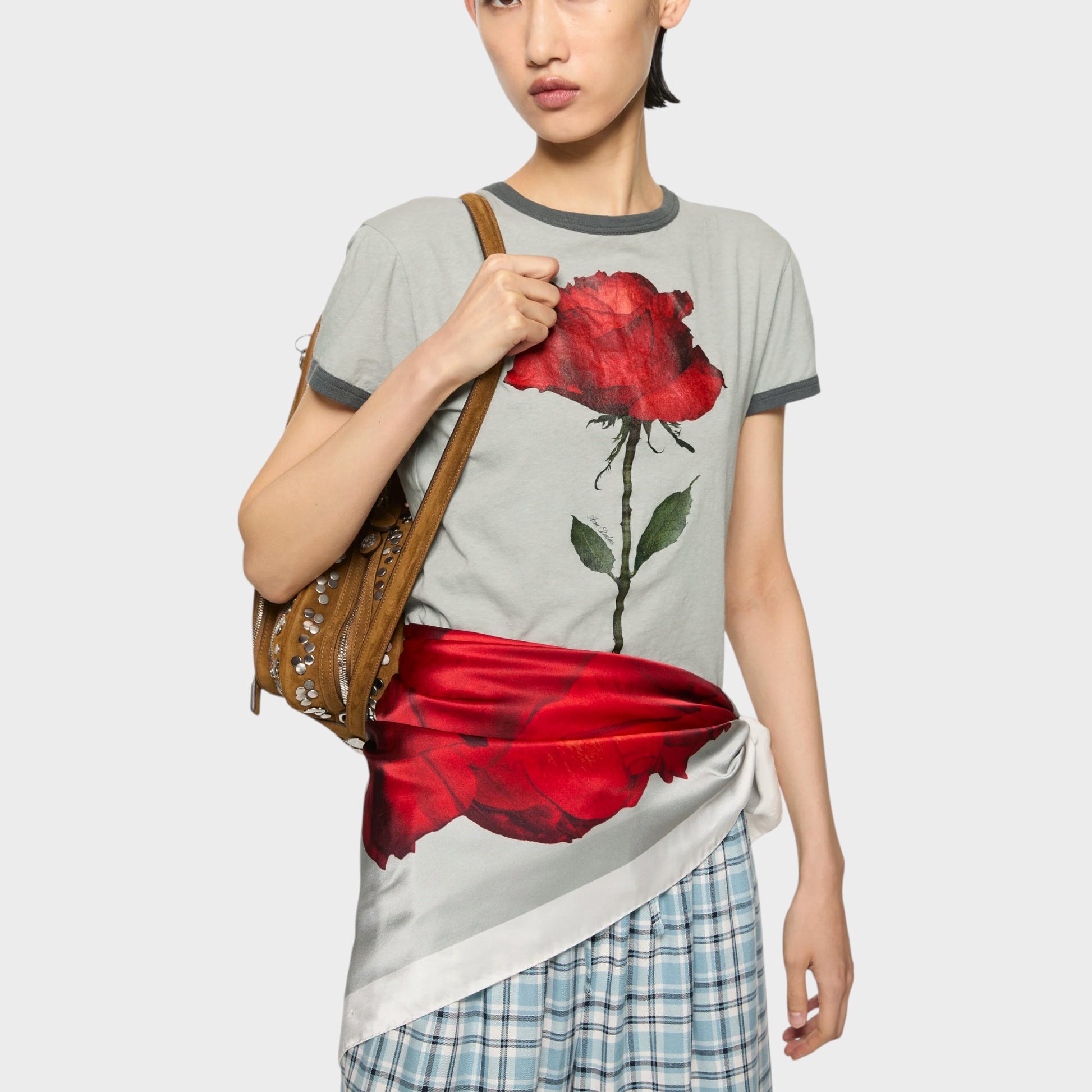 Tasoni grey cotton crew neck t-shirt with a large red rose print and grey trim. Model wears it with a red sash and plaid skirt.