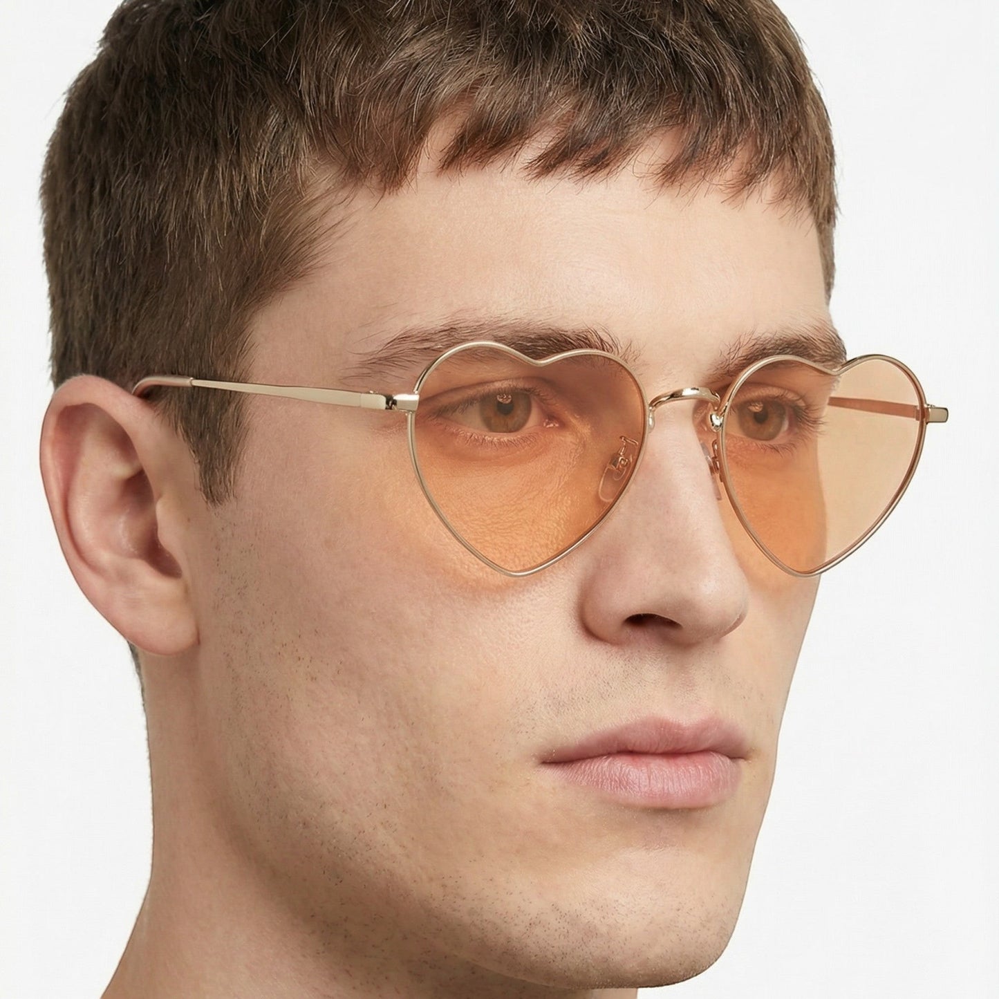 Tasoni Undercover heart-shaped sunglasses with gold frames and orange gradient lenses worn by a man.