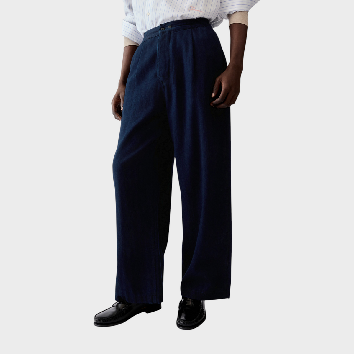 Tasoni Jacquemus Le De-Nimes fluid dark blue denim jeans with a relaxed wide-leg fit worn with a striped shirt.