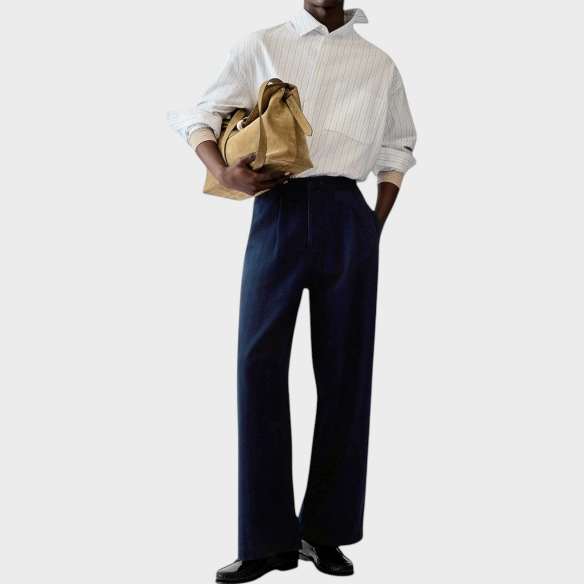 Tasoni model wearing Jacquemus Le De-Nimes fluid dark blue denim pajama jeans with a striped shirt and suede bag