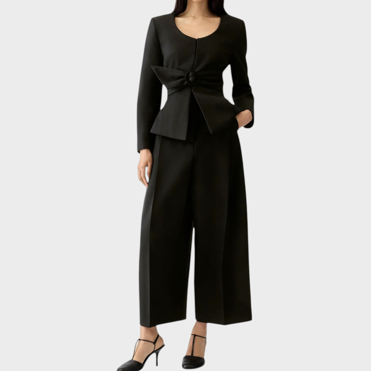 Tasoni Jacquemus La Veste Miami black fitted jacket with a cinched waist and bow detail worn with matching trousers.