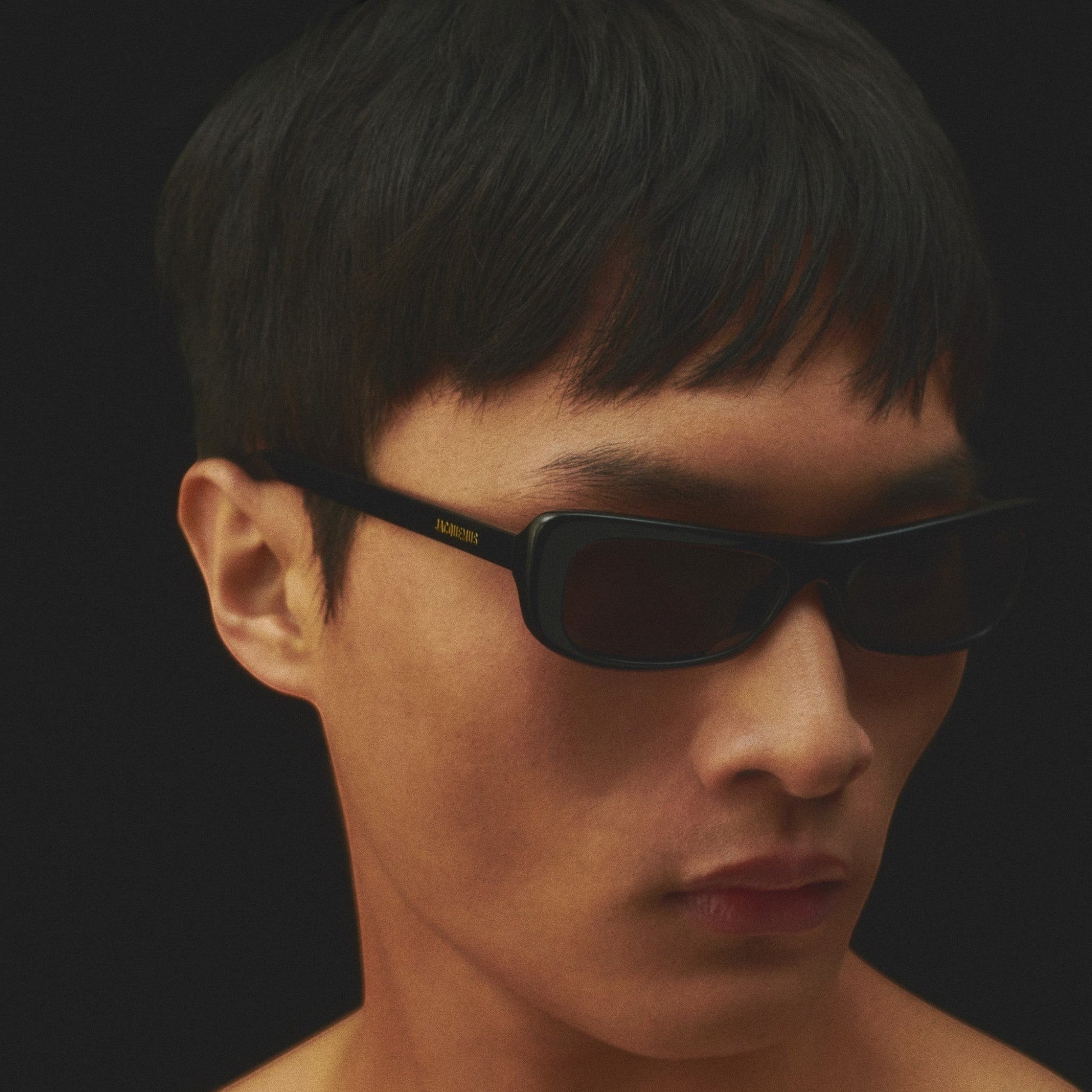 Tasoni Jacquemus Les Lunettes Capri black rectangular sunglasses with dark lenses and gold logo detail.