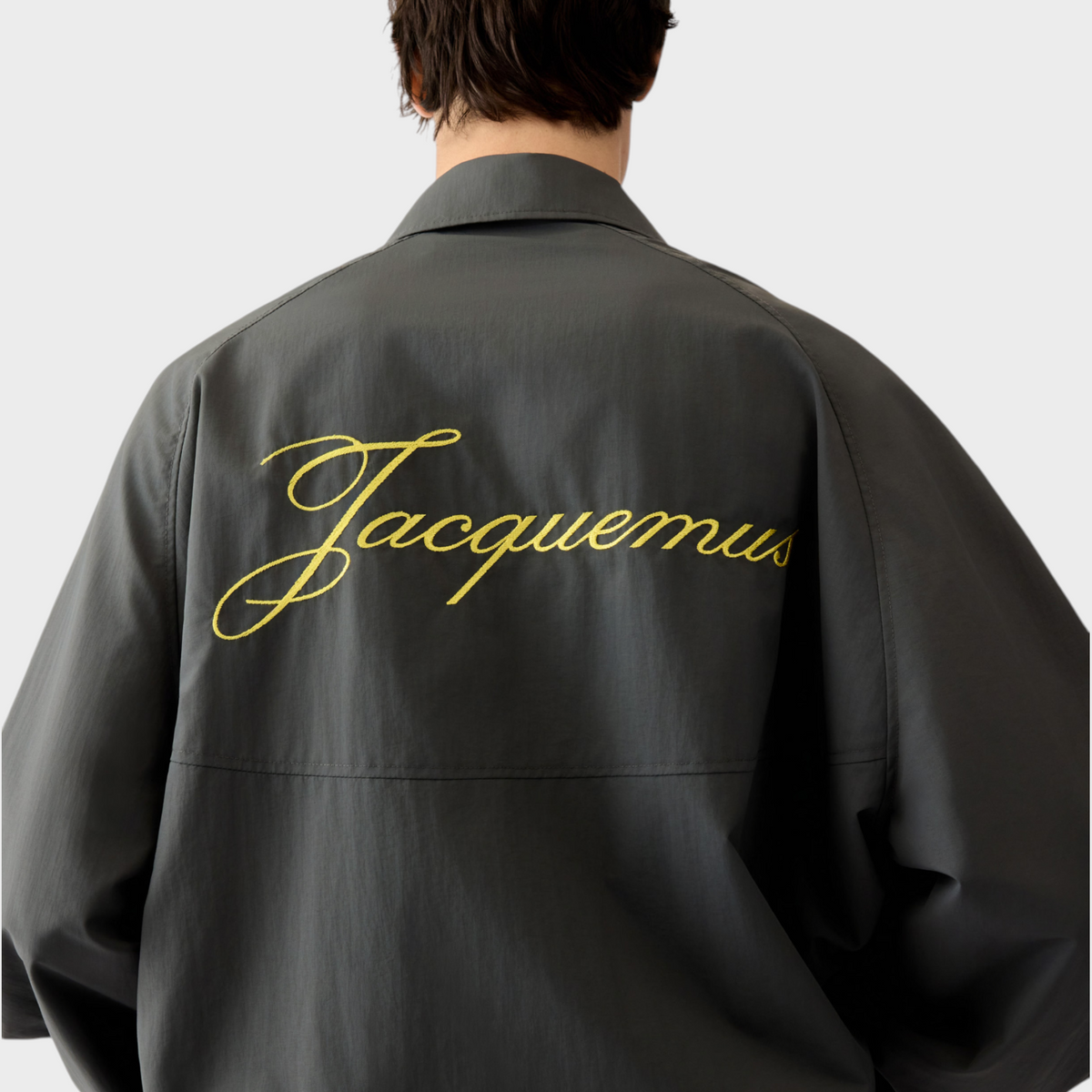 Tasoni Jacquemus Le Coupe-Vent wind breaker jacket in dark grey with yellow embroidered logo on the back