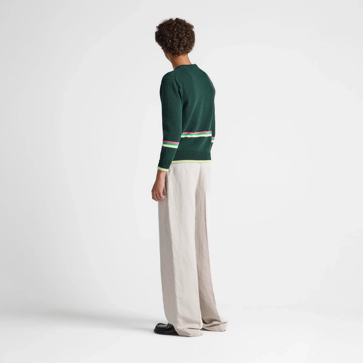 Model wearing a Tasoni JW Anderson green cotton jumper with striped hem details and beige wide-leg trousers.