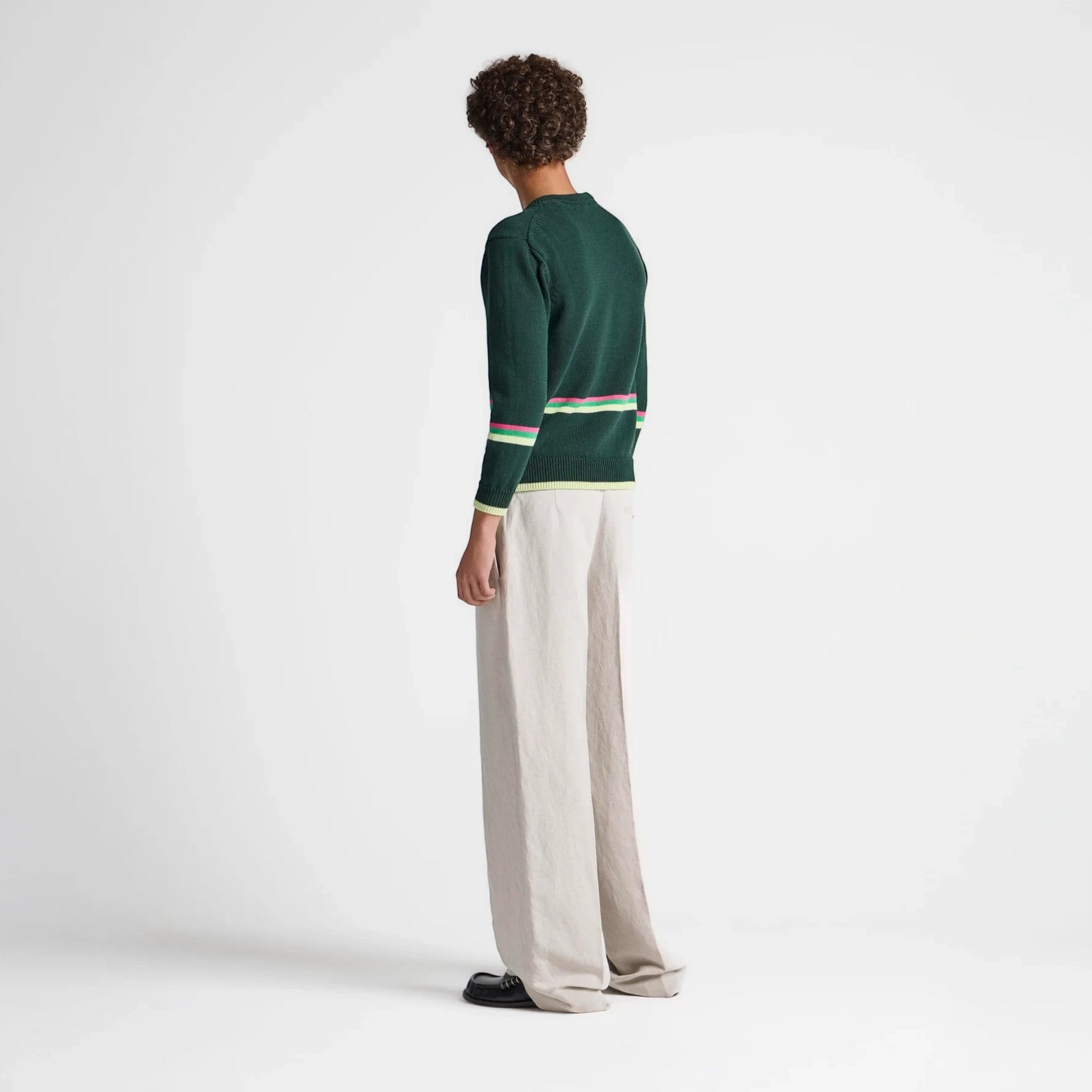 Model wearing a Tasoni JW Anderson green cotton jumper with striped hem details and beige wide-leg trousers.