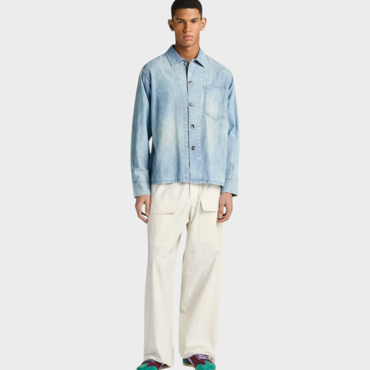 Model wearing a pale blue J.W.Anderson cotton denim shirt with a slant pocket, styled by Tasoni.