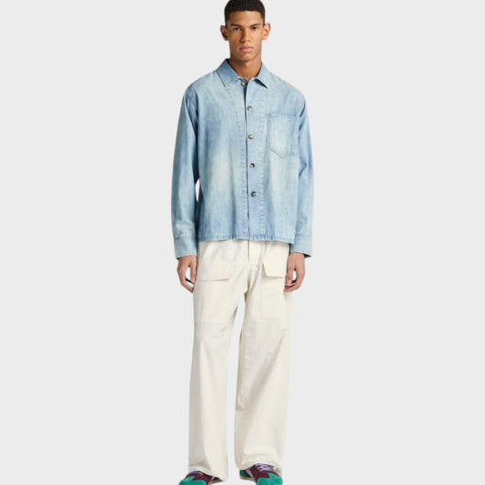 Model wearing a pale blue J.W.Anderson cotton denim shirt with a slant pocket, styled by Tasoni.