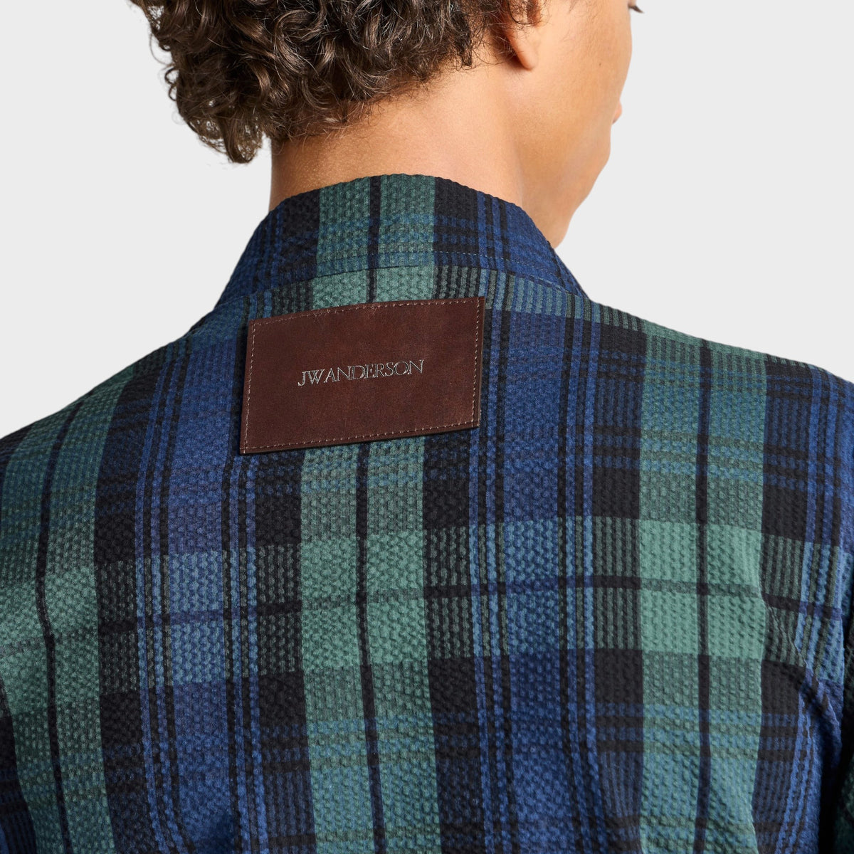 Tasoni J.W.Anderson navy and green cotton check print jacket with a brown leather logo patch on the back collar.
