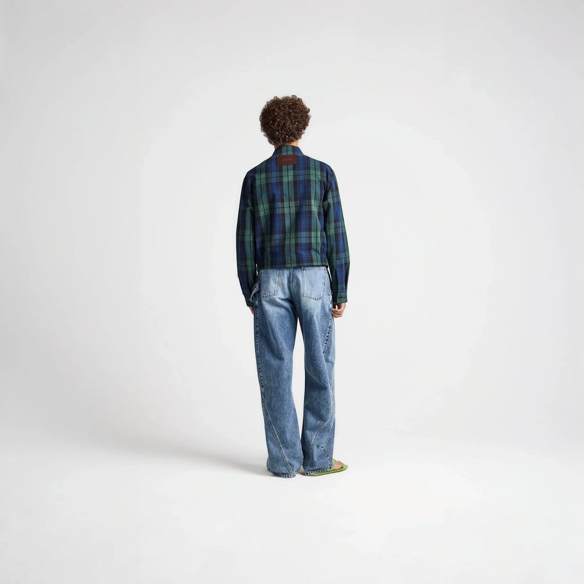 Model wearing Tasoni J.W.Anderson navy and green cotton check print collared zip jacket with blue jeans from behind.