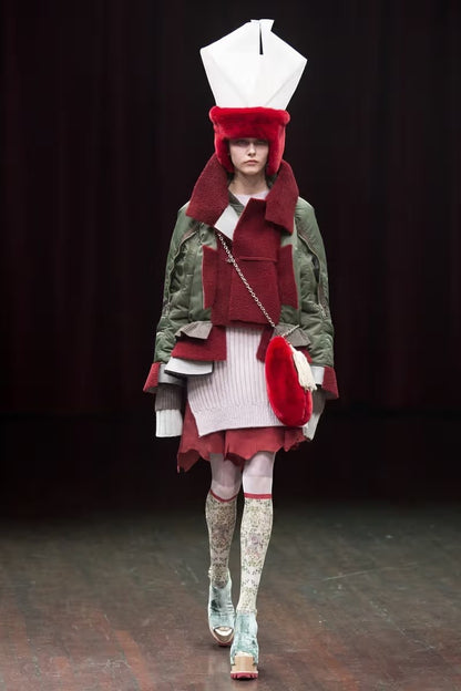 Tasoni Undercover bomber jacket in khaki nylon with burgundy leather and shearling inserts, layered over a pink knit sweater and red skirt.