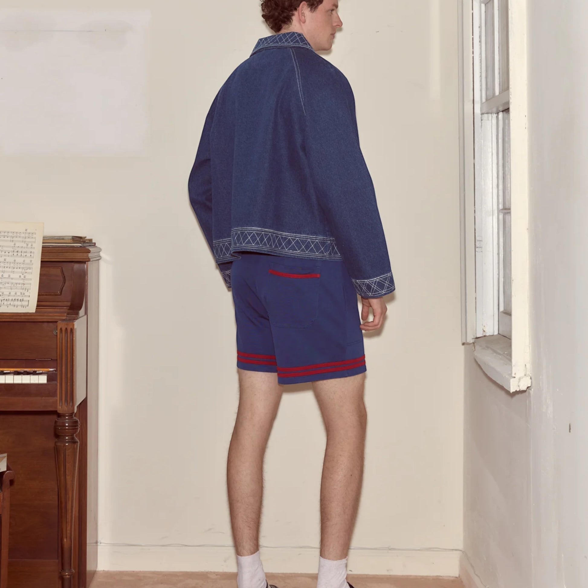 Tasoni Bode Lakewood Technical Shorts in blue with red stripe detail. Model wearing shorts and denim jacket.